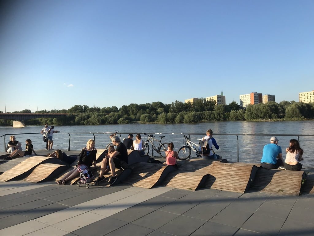 Kartu ir atskirai. Žvelgiant į miestą ir į upę. Prisėdus ar prigulus. Vienas iš daugelio sėdėjimo scenarijų pasiūlymų Vyslos krantinėje Varšuvoje. 